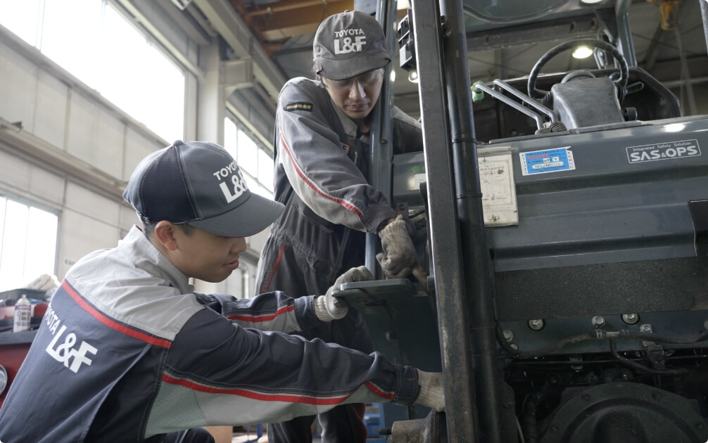 先輩の指示の元フォークリフトの整備をする松田さん